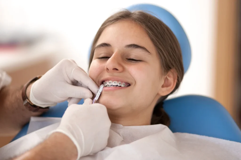 Paciente Sorrindo Enquanto O Dentista Ajusta Seu Aparelho Fixo Paciente Sorrindo Enquanto O Dentista Ajusta Seu Aparelho Fixo