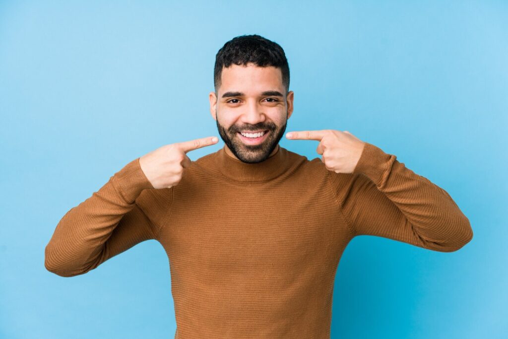 Young Latin Man Against Blue Wall Isolated Smiles Pointing Fingers Mouth 1187 54062 Young Latin Man Against Blue Wall Isolated Smiles Pointing Fingers Mouth 1187 54062